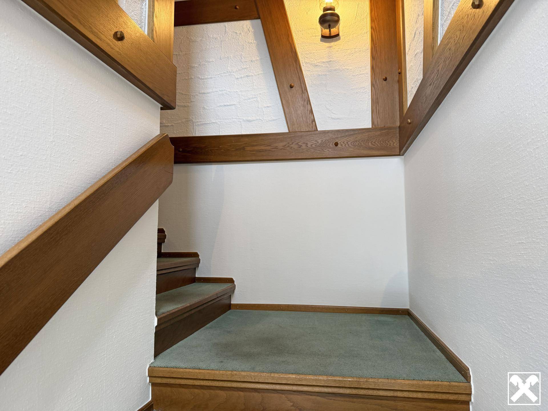 Treppenaufgang mit Holzgeländer und Teppichboden in traditionellem Stil.