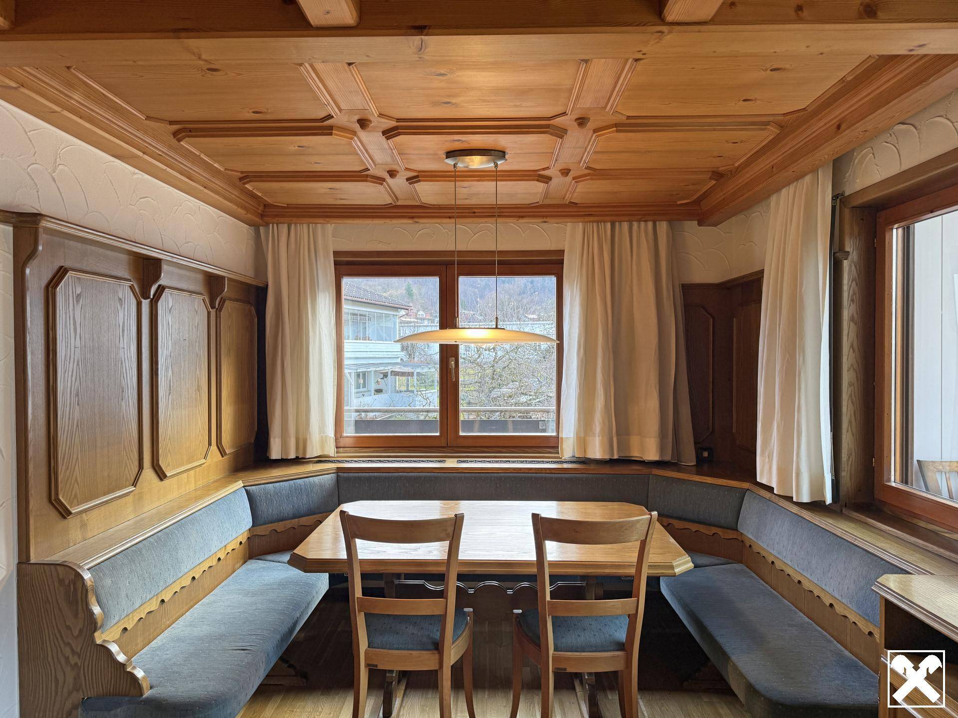 Gemütlicher Essbereich mit Holztäfelung, Kassettendecke und traditionellen Sitzbänken.