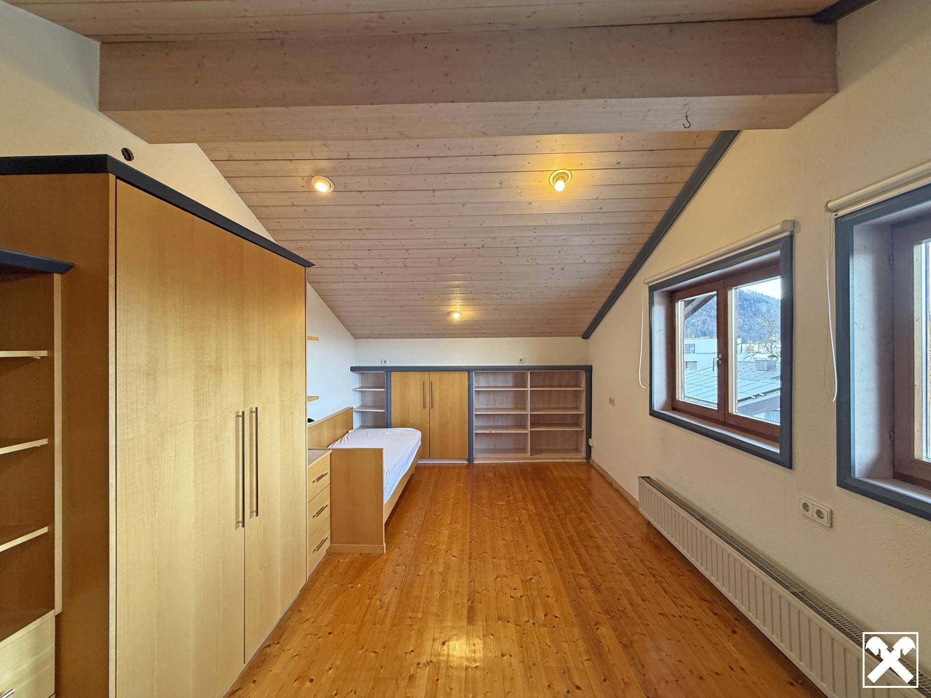 Geräumiges Schlafzimmer im Dachgeschoss mit Holzbalkendecke und Einbauschränken.