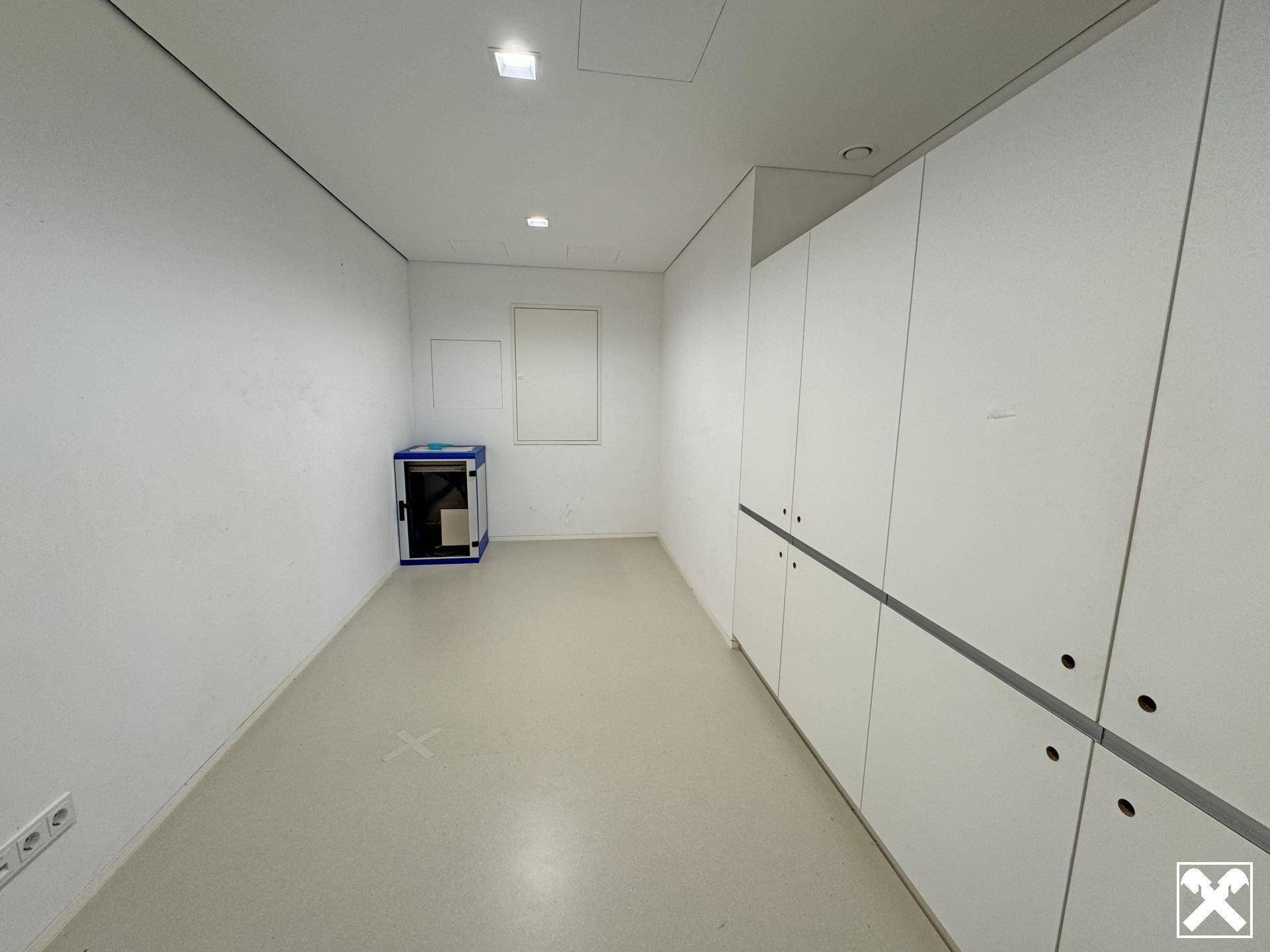 Funktionaler Abstellraum mit weißen Schränken, hellem Boden und einem kleinen blauen Schrank.