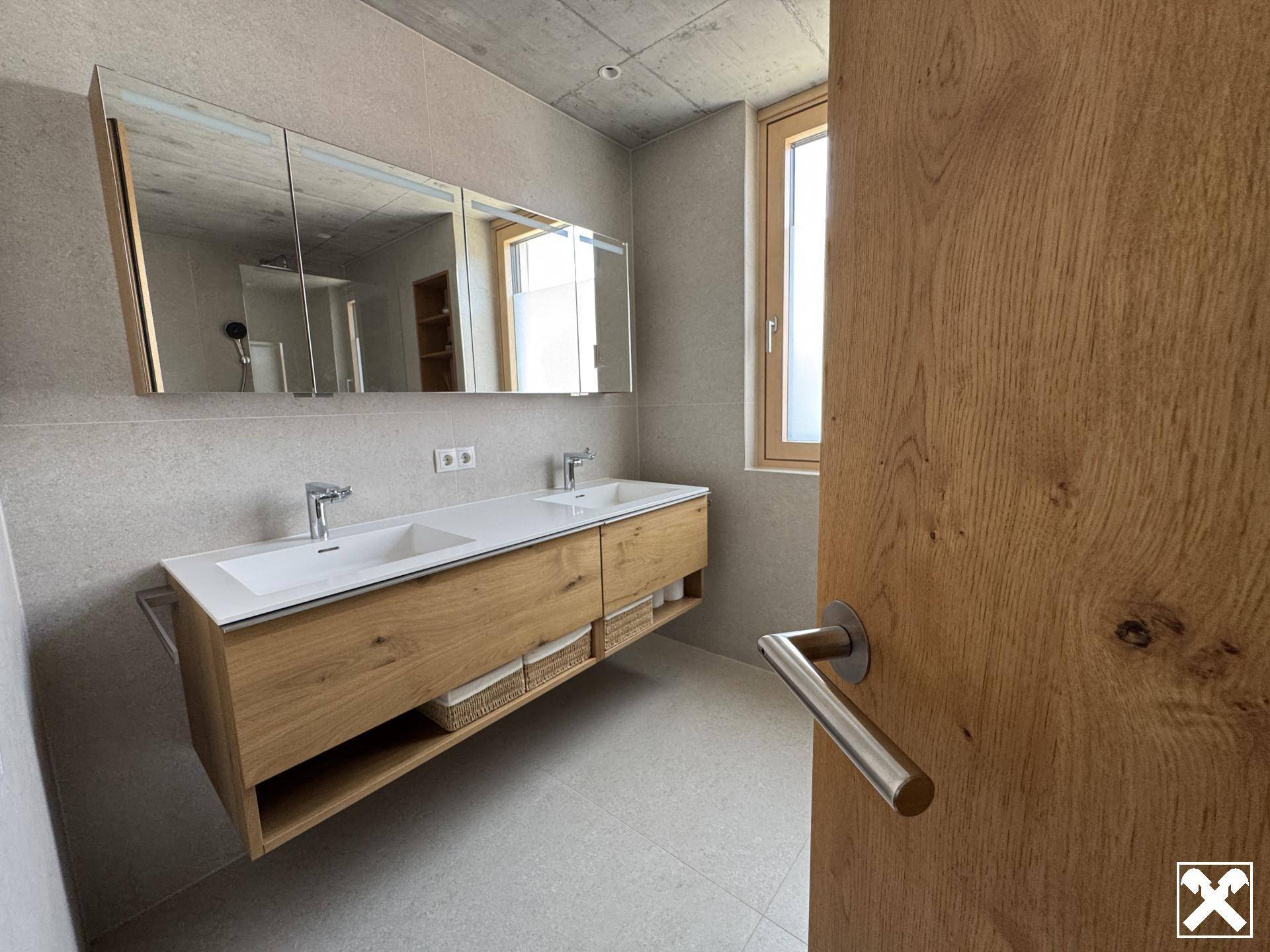 Modernes Badezimmer mit Doppelwaschbecken, Holzunterschrank und Spiegelschrank.