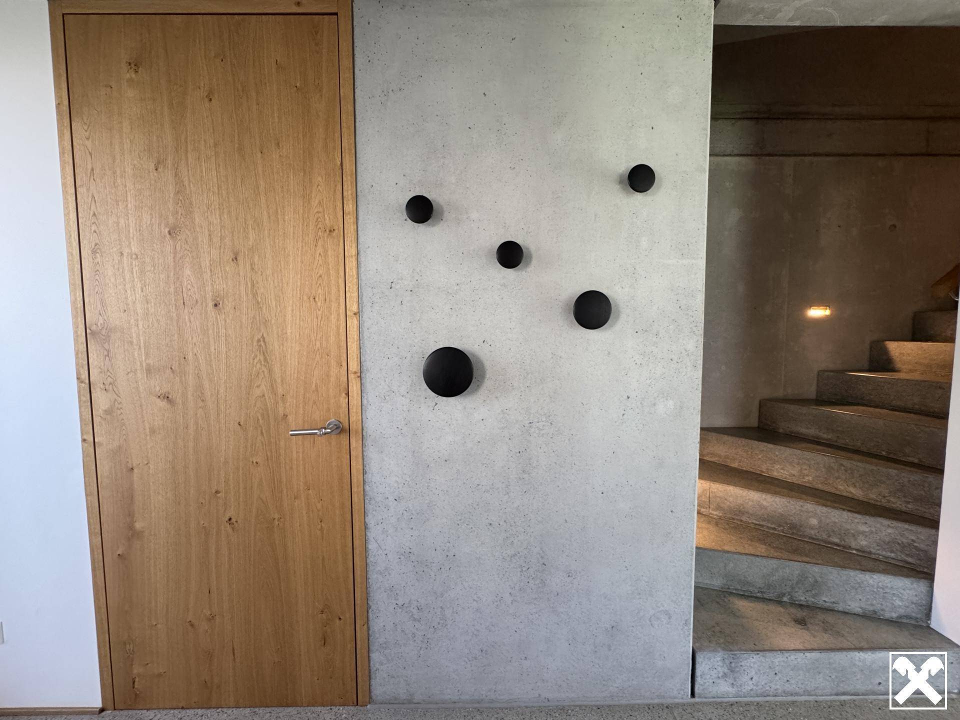 Moderner Flur mit Holztür, Betonwand und dekorativen Wandhaken.
