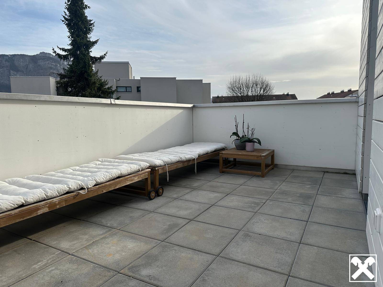 Geräumige Dachterrasse mit Sonnenliegen und Blick auf die umliegende Landschaft.
