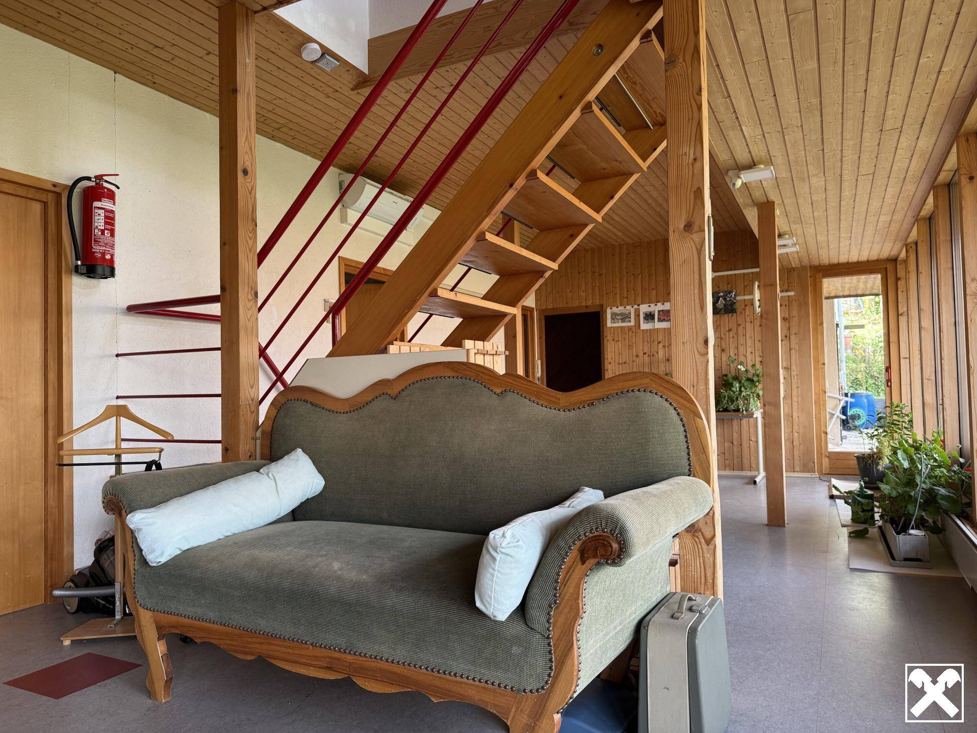 Gemütlicher Eingangsbereich mit Holztreppe, Vintage-Sofa und holzvertäfelten Wänden, strahlt rustikalen Charme aus.