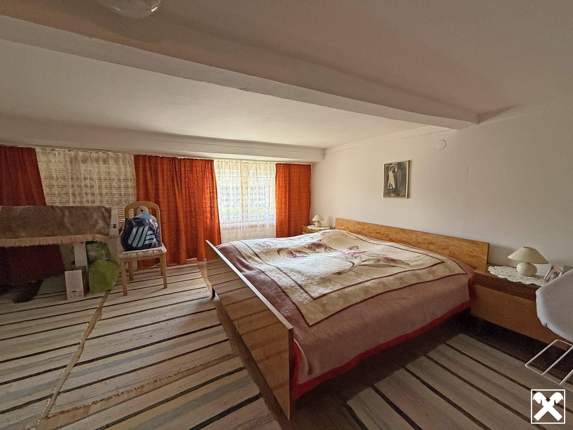 Geräumiges Schlafzimmer mit großem Bett, Holzrahmen und farbigen Vorhängen für eine wohnliche Atmosphäre.
