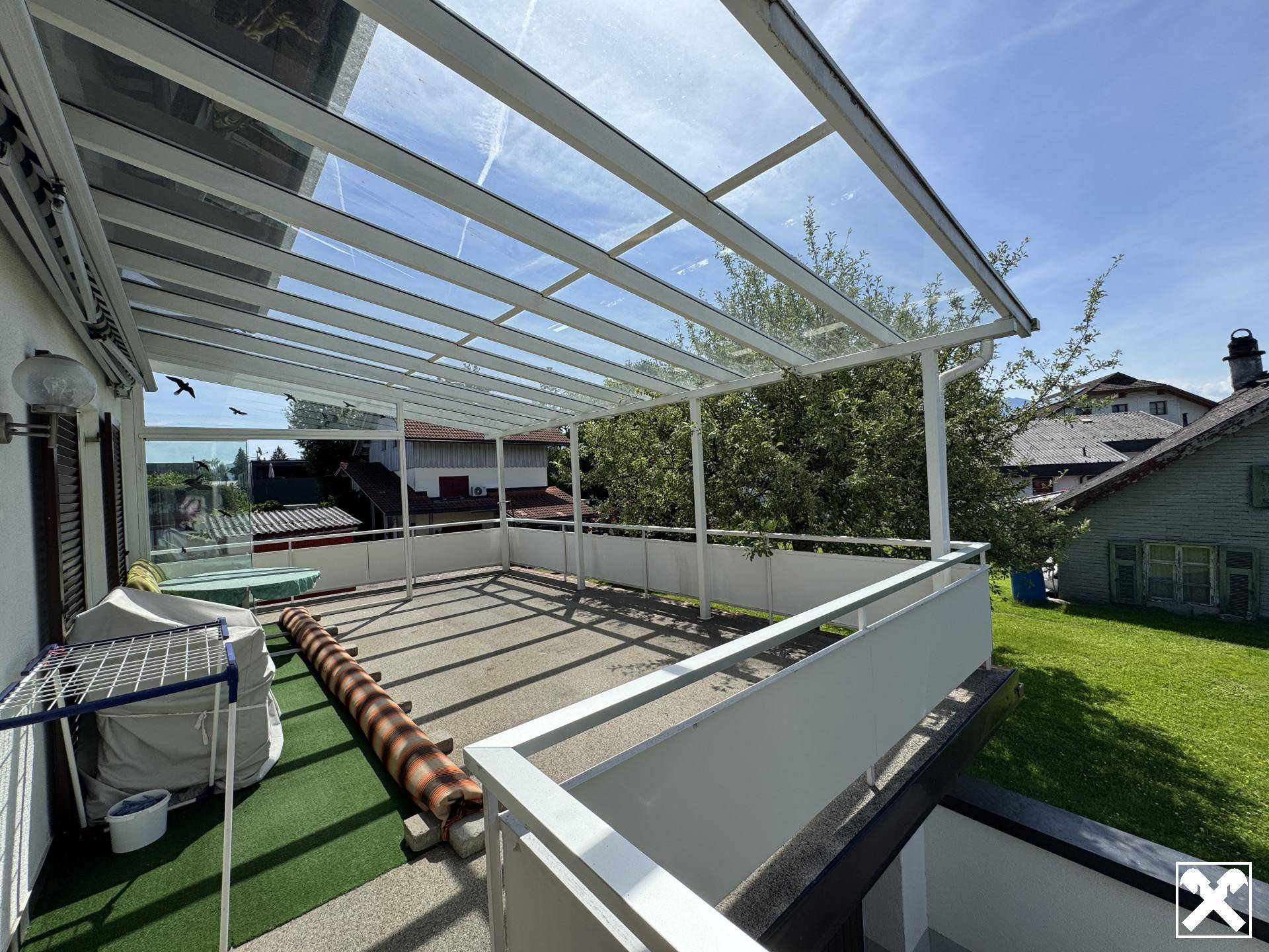 Große überdachte Terrasse mit Glasdach und Blick ins Grüne, ideal für entspannte Stunden im Freien.