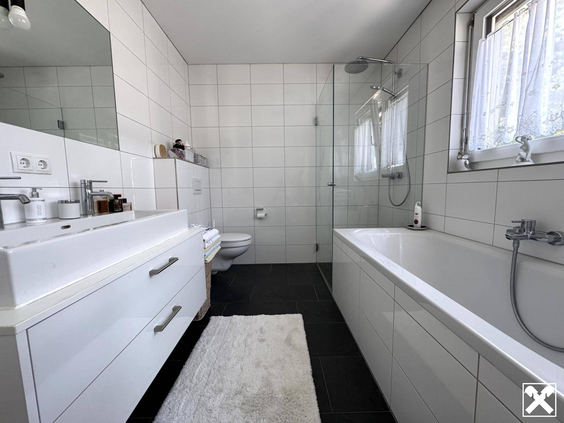 Modernes Badezimmer mit Badewanne, begehbarer Dusche, Einzelwaschbecken und Fenster für Tageslicht.