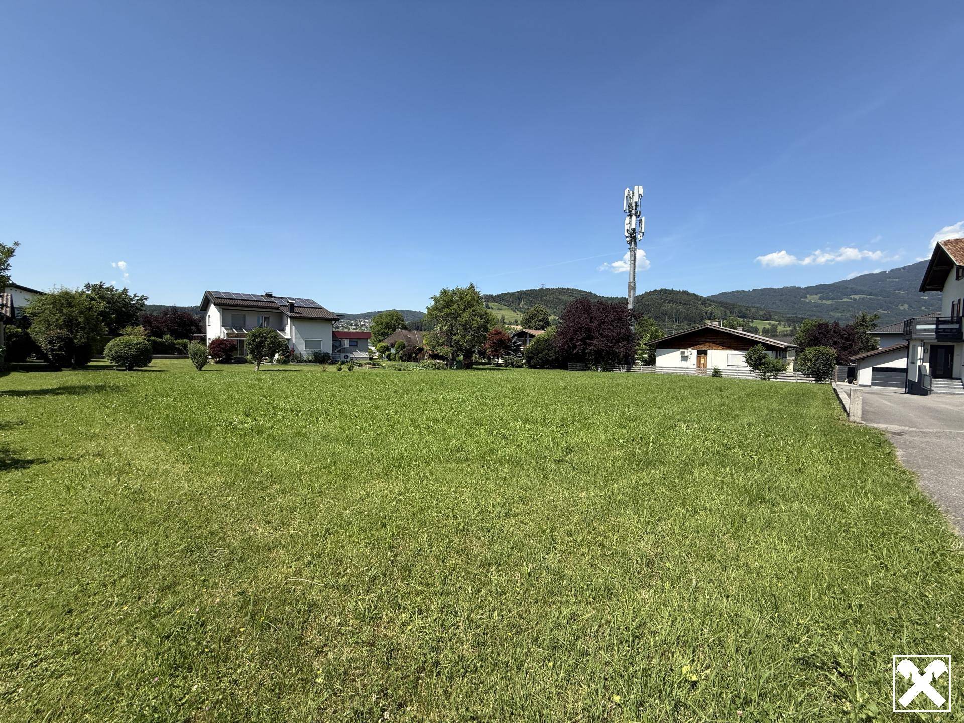 Weitläufiges grünes Grundstück mit sonniger Lage und Blick auf die umliegende Landschaft und Berge.