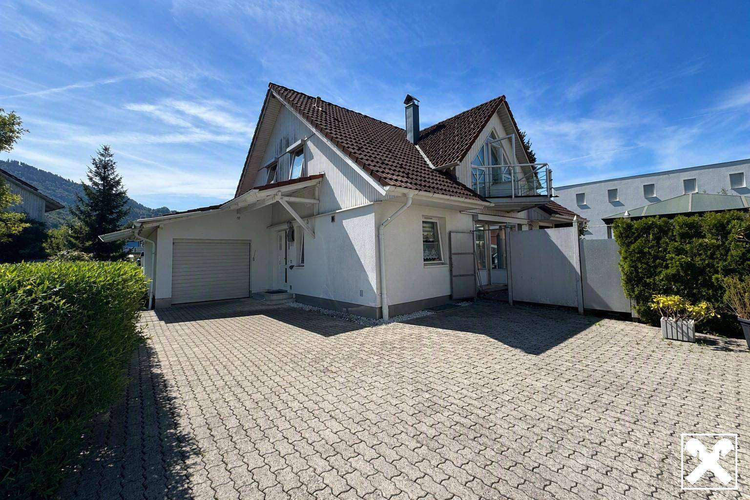 Vorderansicht des Hauses mit gepflasterter Einfahrt und integrierter Garage.