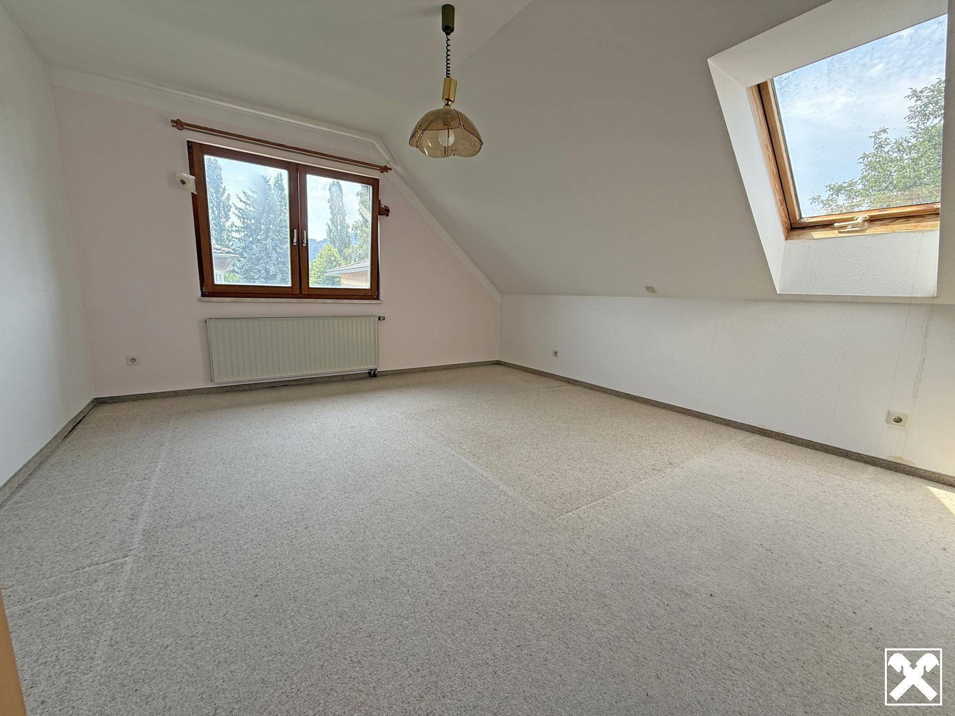 Helles Schlafzimmer im Dachgeschoss mit Teppichboden, Fenster und Dachfenster.