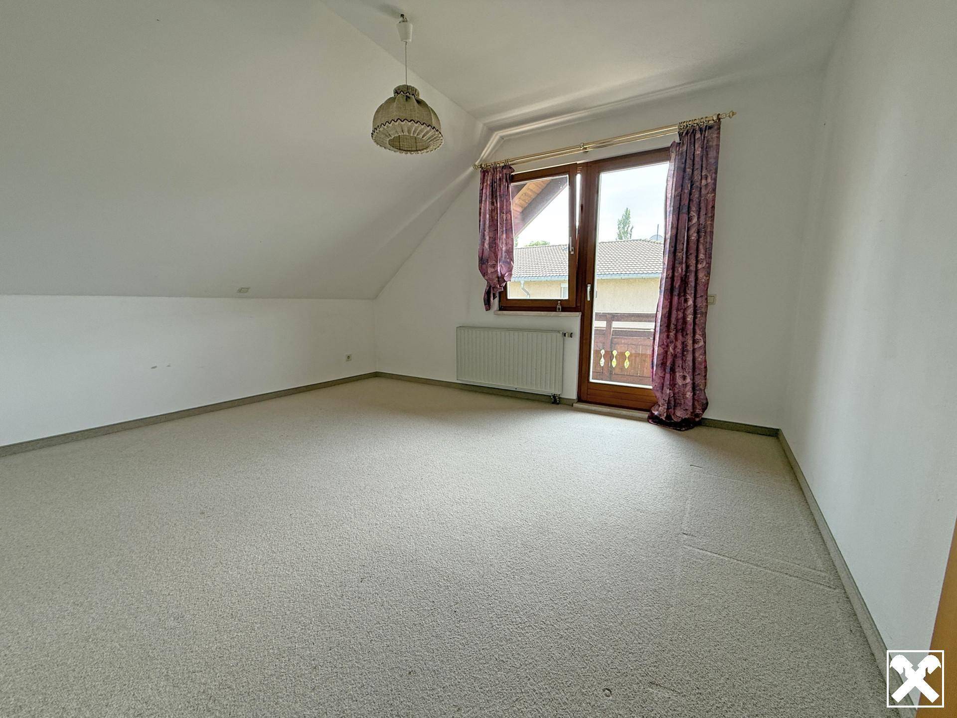 Schlafzimmer im Dachgeschoss mit Teppichboden und Zugang zu einem Balkon.