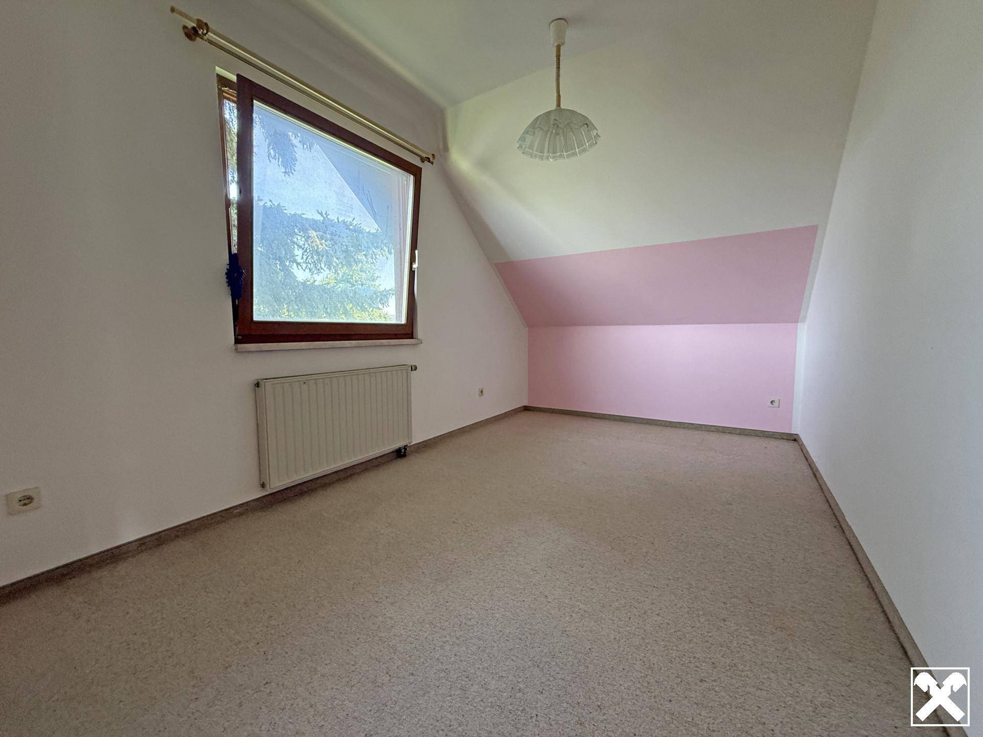 Dachschlafzimmer mit schräger Decke, rosa Akzentwand und Teppichboden.