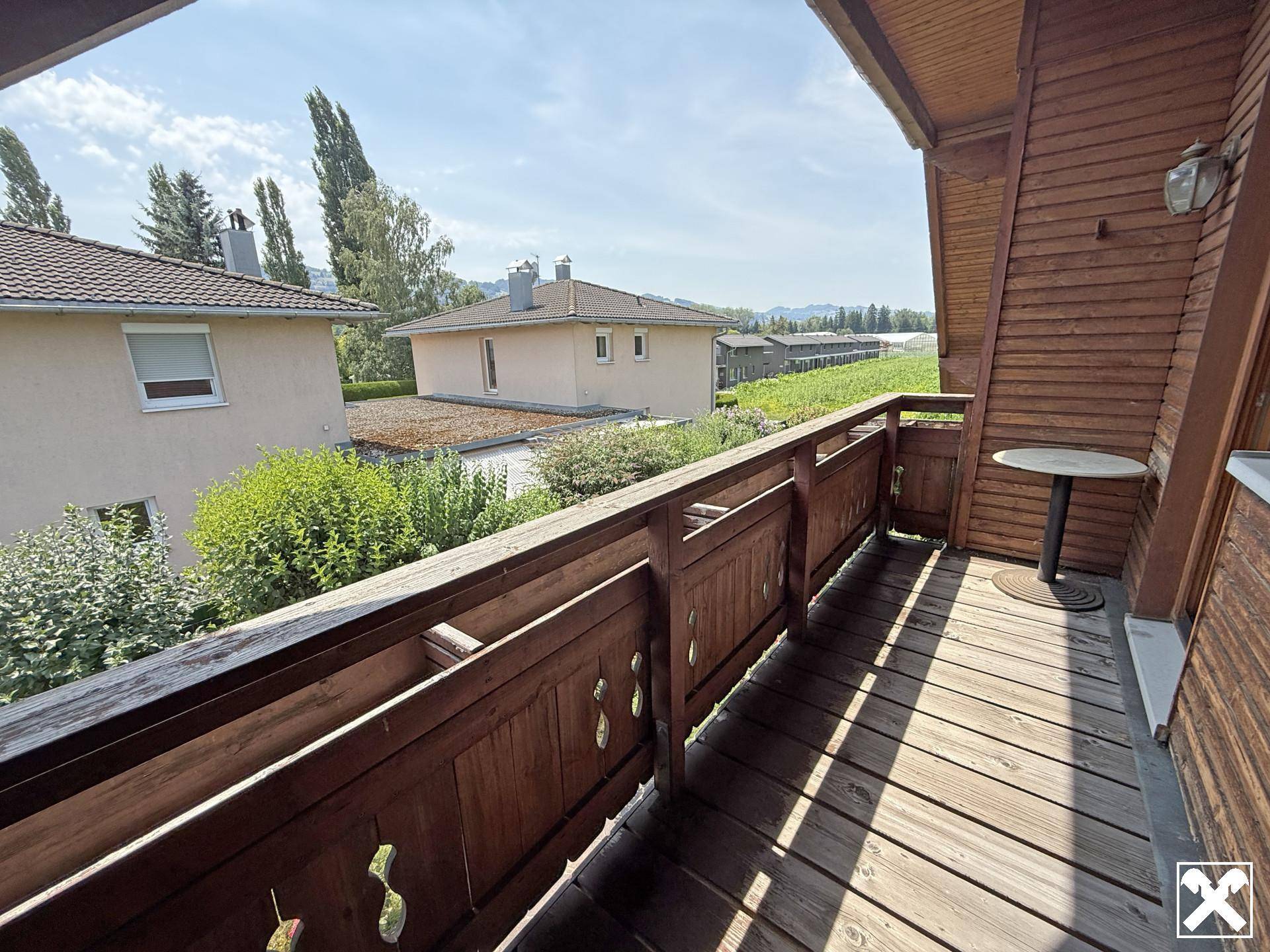Traditioneller Holzbalkon mit kleinem Tisch und Blick auf die Umgebung und Weinberge.