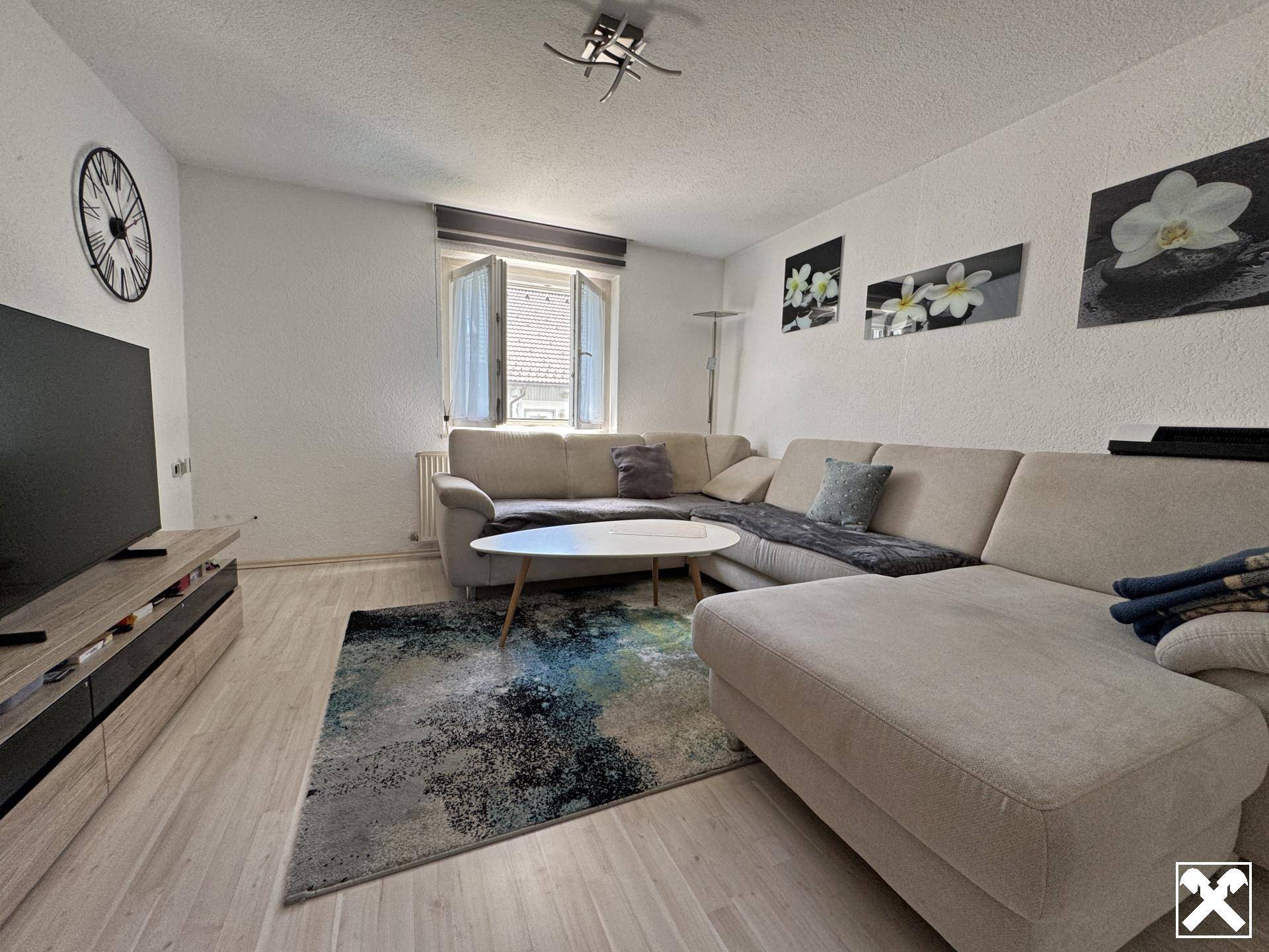 Helles Wohnzimmer mit großem Ecksofa, modernem Teppich und hellem Laminatboden.