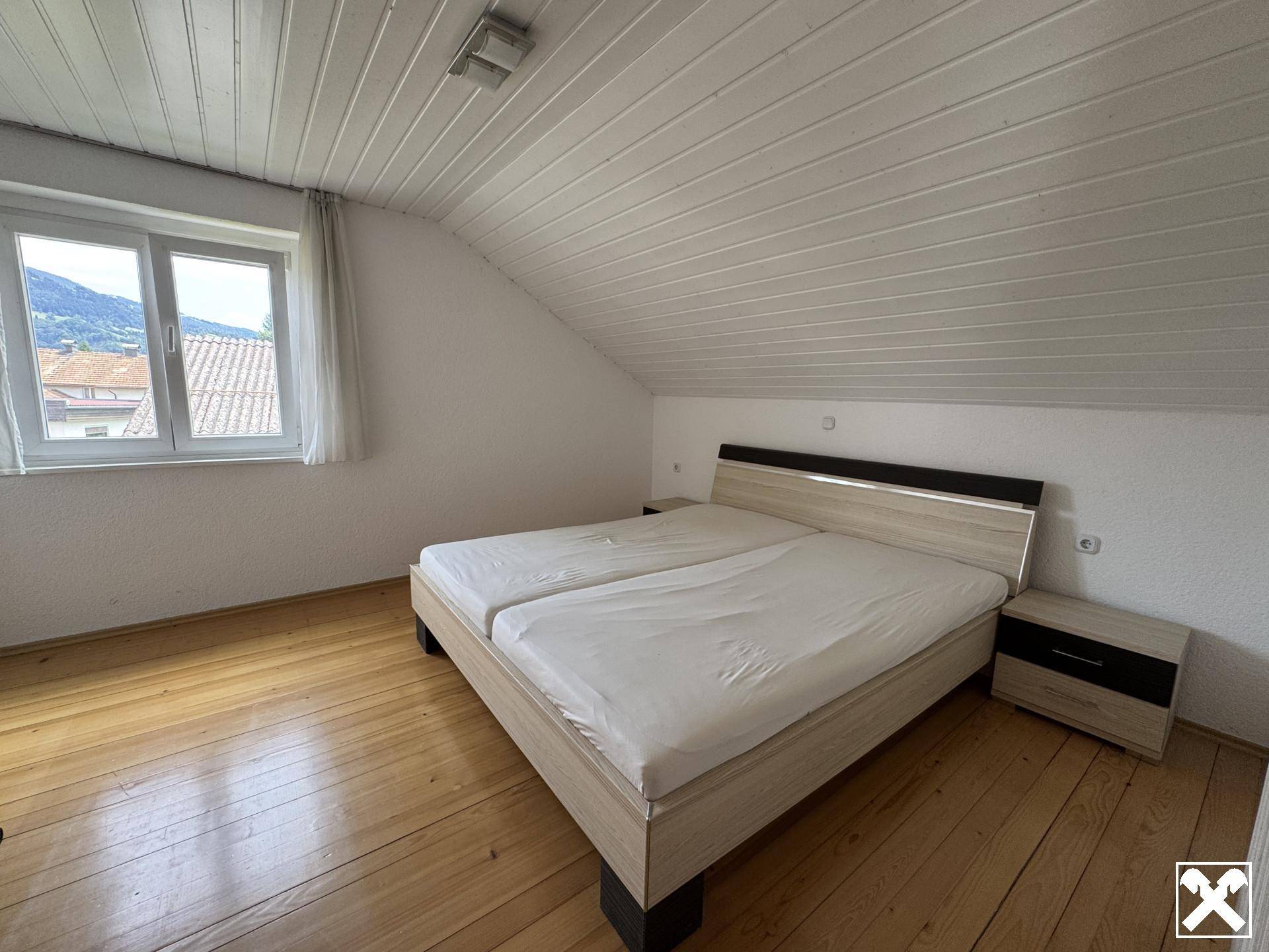 Gemütliches Schlafzimmer im Dachgeschoss mit Doppelbett, Holzparkett und Dachschräge.