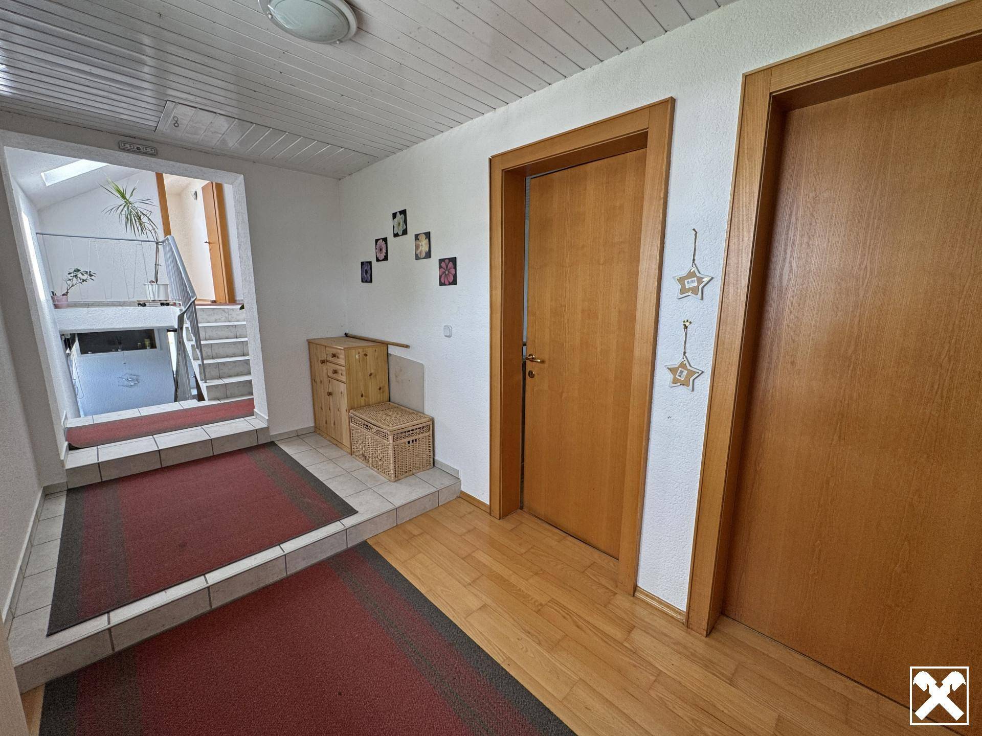 Eingangsbereich mit Holzfußboden, Holztüren und Zugang zum Treppenhaus.