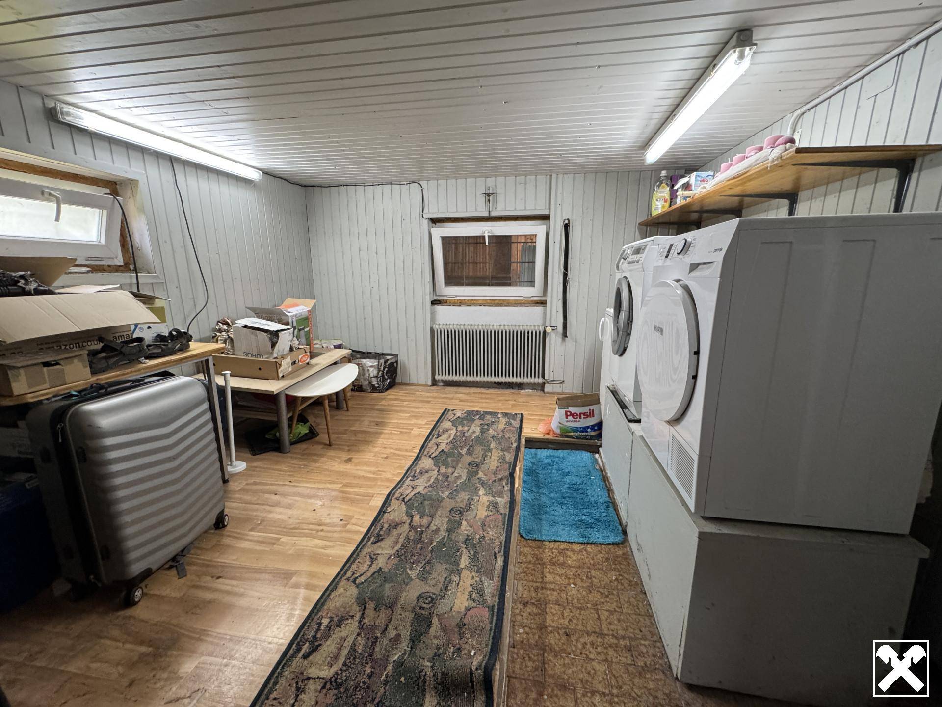 Geräumiger Hauswirtschaftsraum im Keller mit Waschmaschine, Trockner und Stauraum.