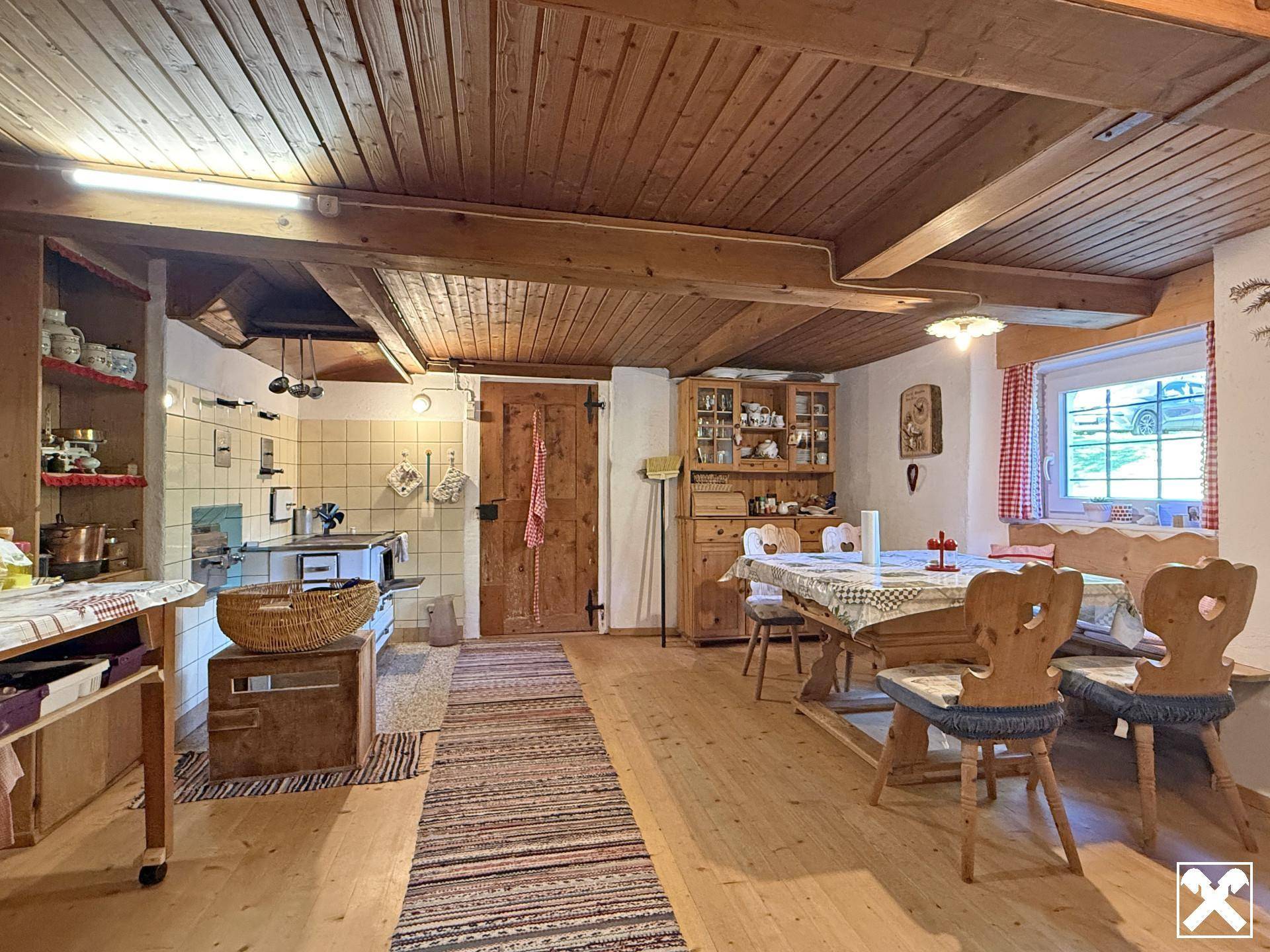 Rustikale Wohnküche mit Holzbalkendecke, traditionellem Essbereich und gefliestem Kochbereich.