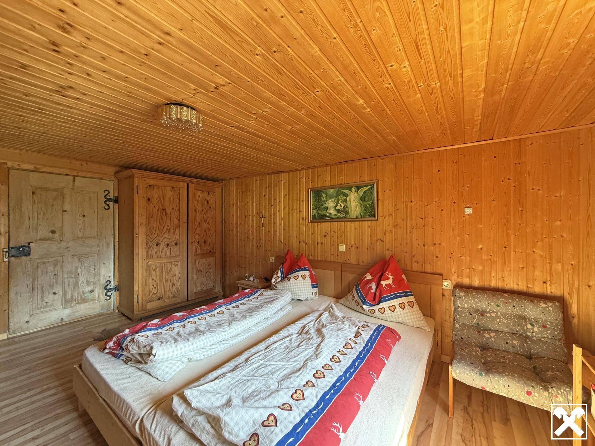 Schlafzimmer mit Holztäfelung, Doppelbett und einem Kleiderschrank in rustikalem Design.
