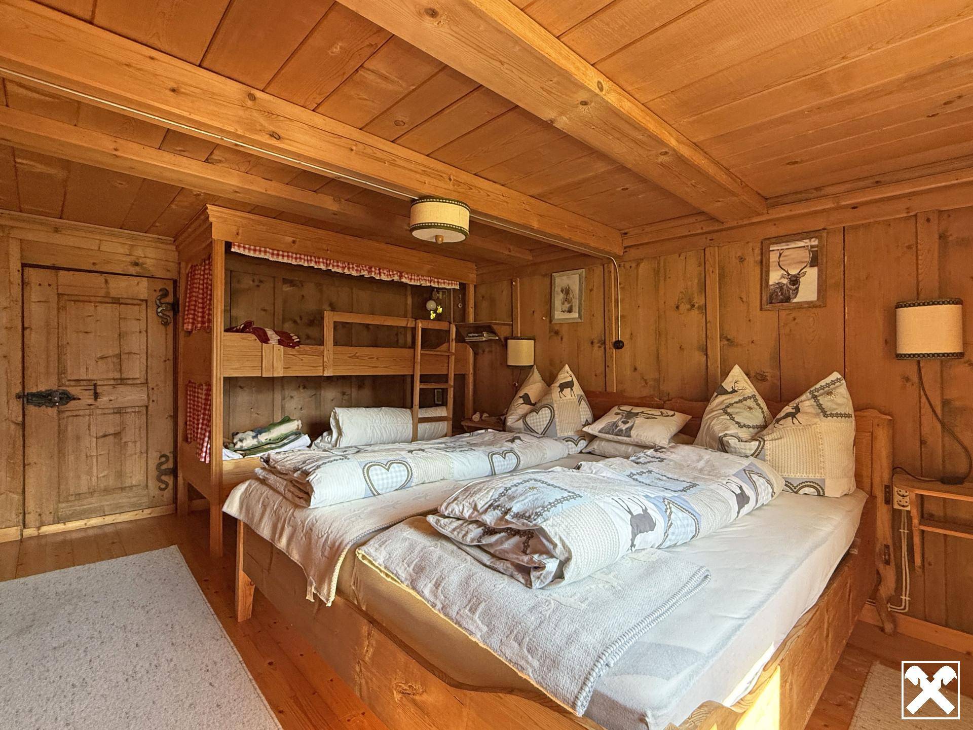 Gemütliches Schlafzimmer mit Holzwänden, Holzbalkendecke und einem Etagenbett in traditionellem Stil.