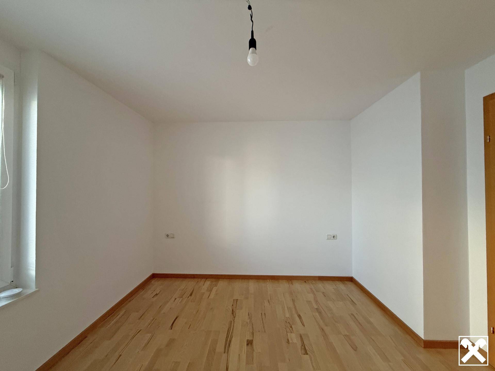 Leerer Raum mit hellem Parkettboden und weißen Wänden, bereit zur individuellen Gestaltung.