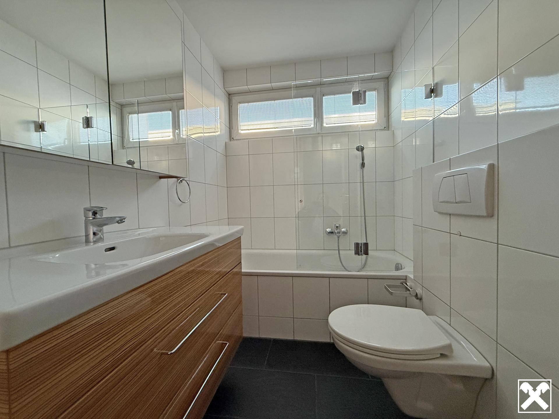 Modernes Badezimmer mit Badewanne, Waschbecken und WC, ausgestattet mit weißen Fliesen.