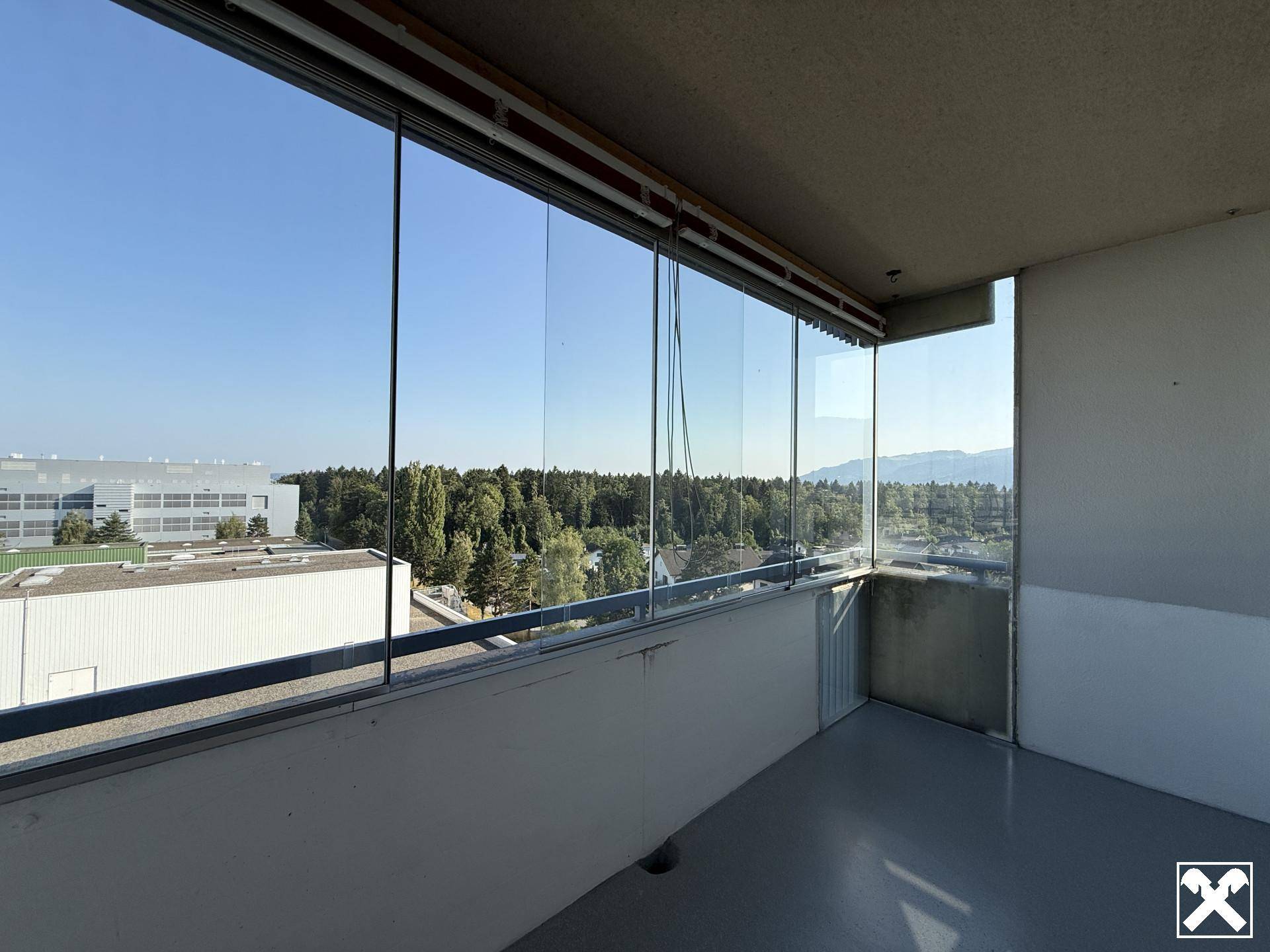 Verglaste Loggia mit Panoramablick über die Stadt und die umliegende grüne Landschaft.