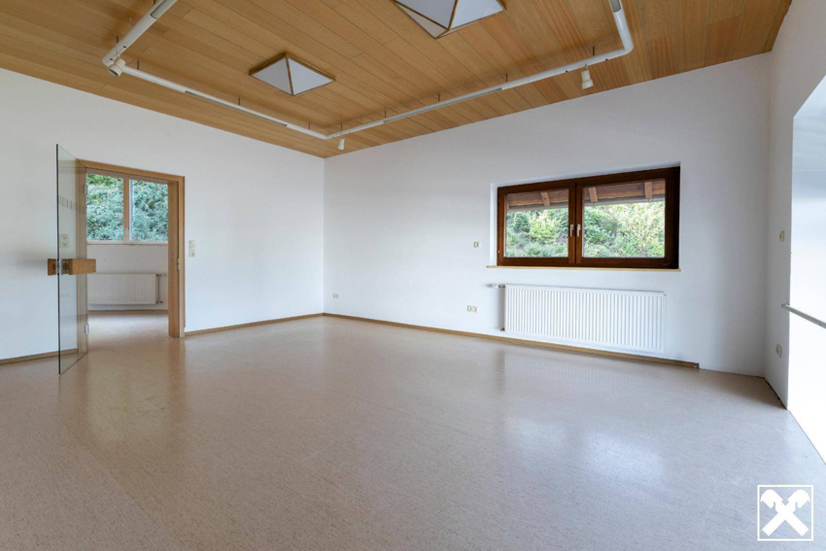 Heller Raum mit Holzdecke und großem Fenster, bietet viel Tageslicht und eine angenehme Atmosphäre.