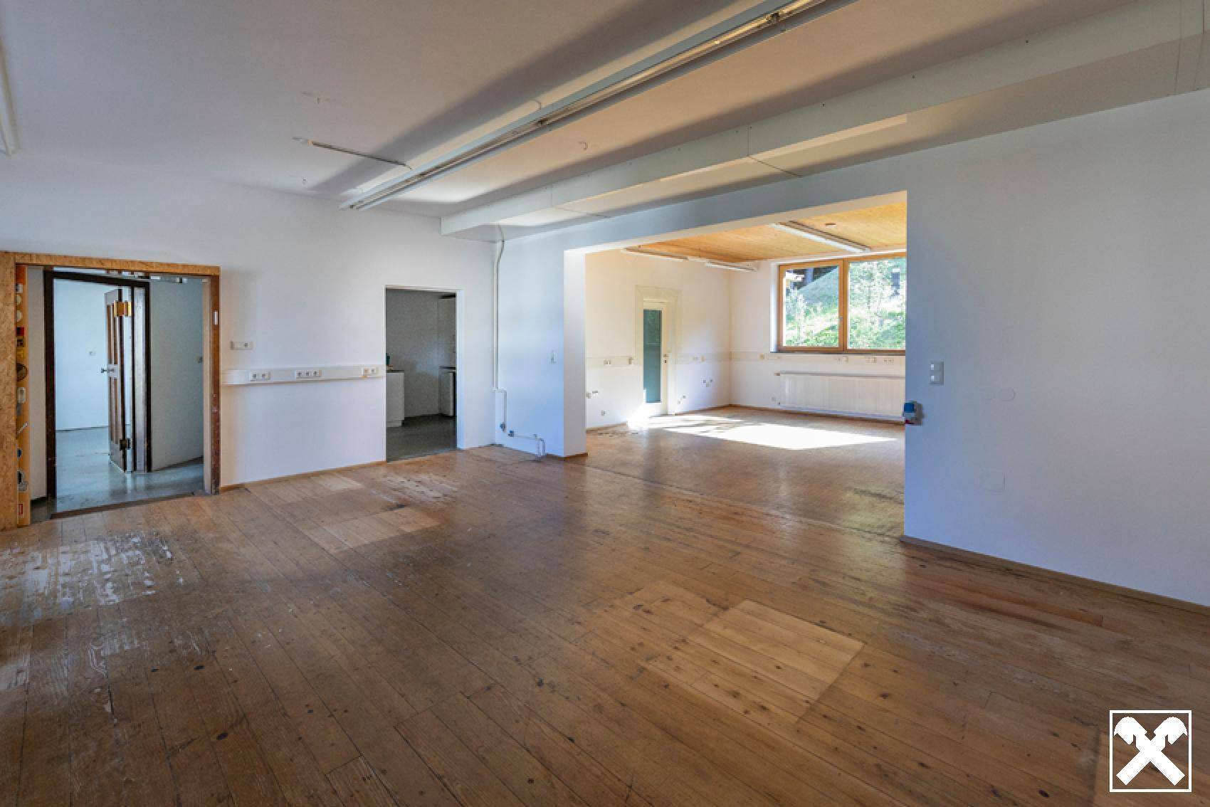 Geräumiger, heller Raum mit Holzboden und sichtbaren Deckenbalken, vielseitig nutzbar.