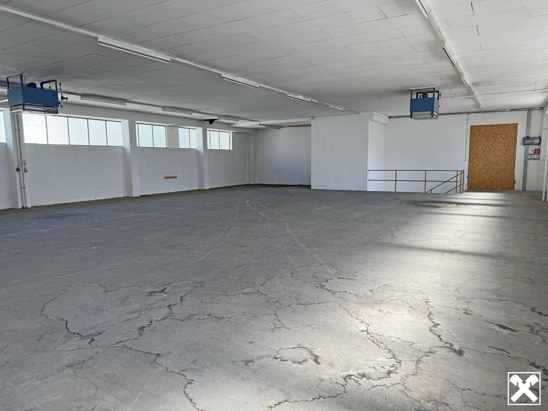 Helle Lagerhalle mit Betonboden, hohen Decken und Lüftungsanlagen, bereit zur Nutzung.