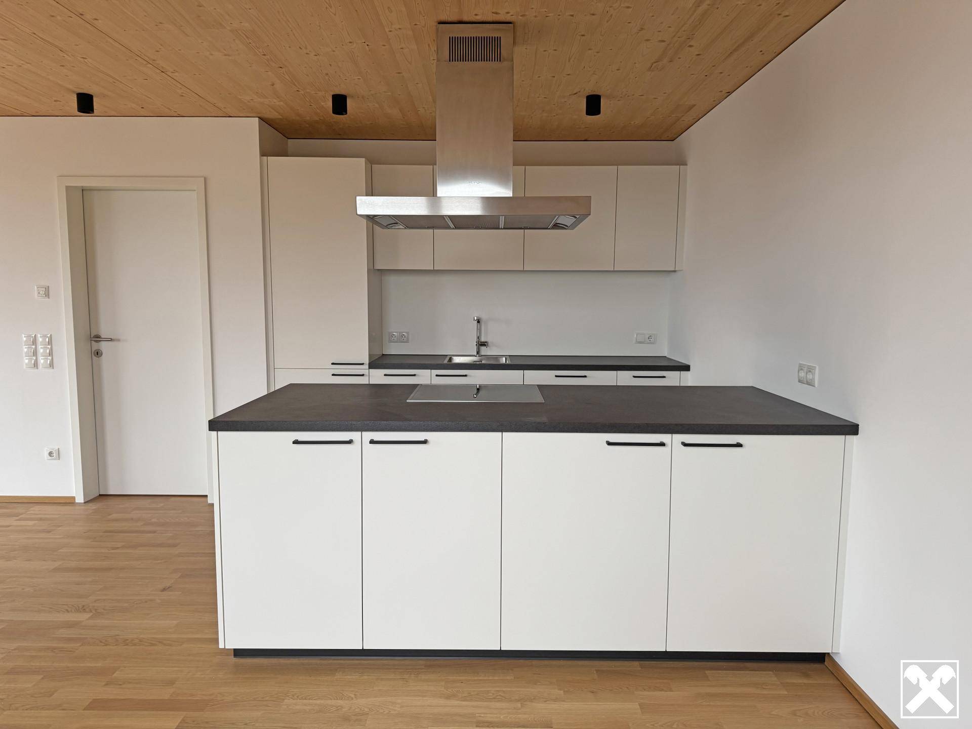 Detailansicht der modernen Einbauküche mit Kücheninsel und Dunstabzugshaube.