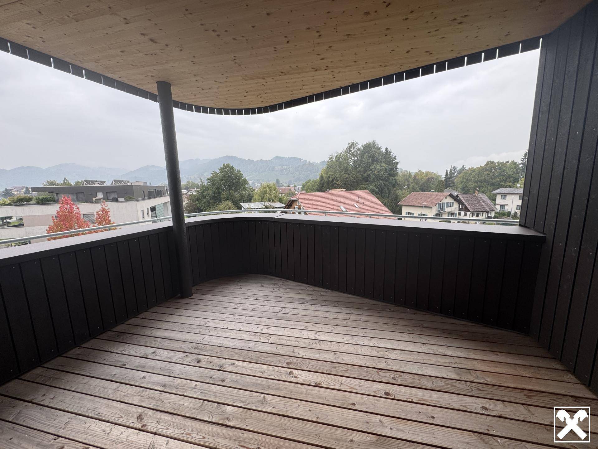 Geräumiger Holzbalkon mit schöner Aussicht auf die umliegende Landschaft und Berge.