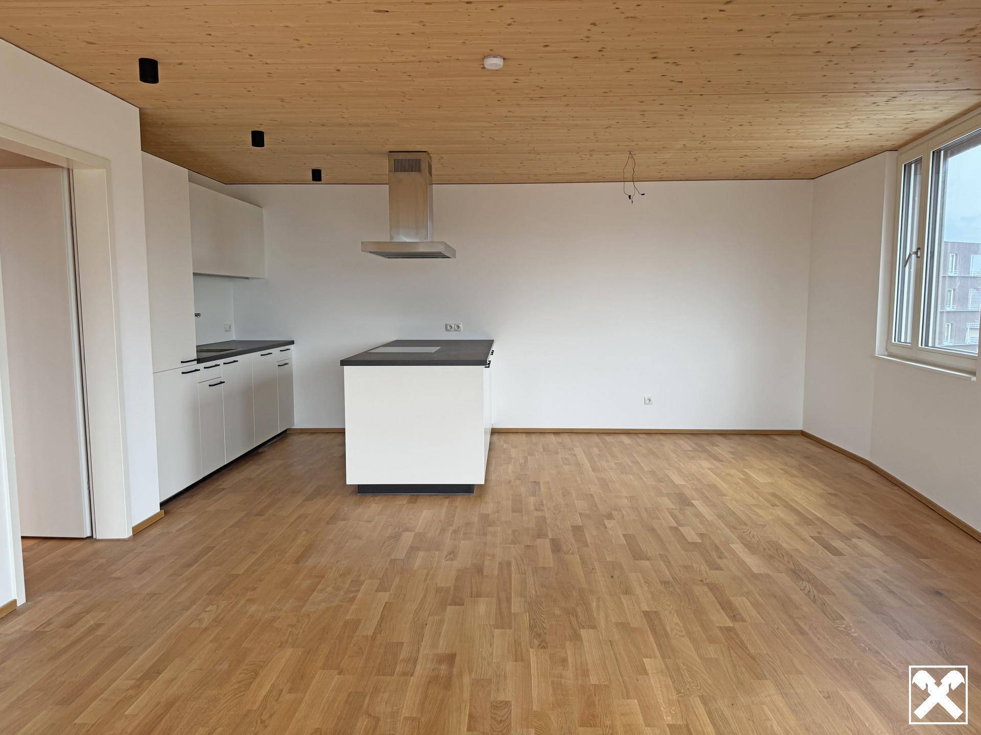 Offene Küche mit moderner Kücheninsel und Holzboden in einem hellen Wohnbereich.