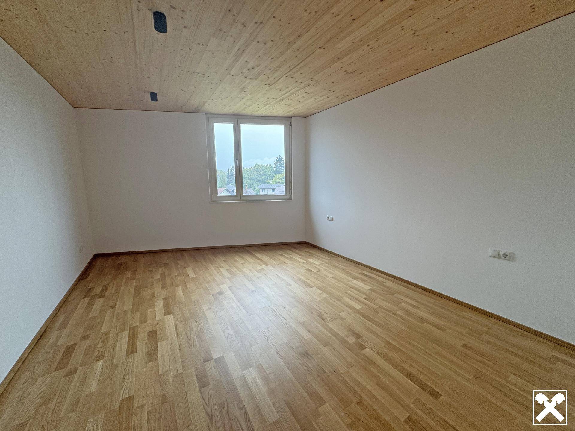 Helles Zimmer mit Holzboden und einem Fenster, ideal als Schlaf- oder Arbeitszimmer.