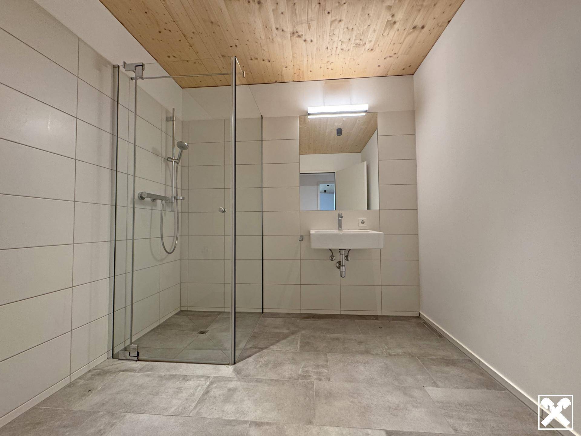 Modernes Badezimmer mit großer begehbarer Dusche und hellen Fliesen.