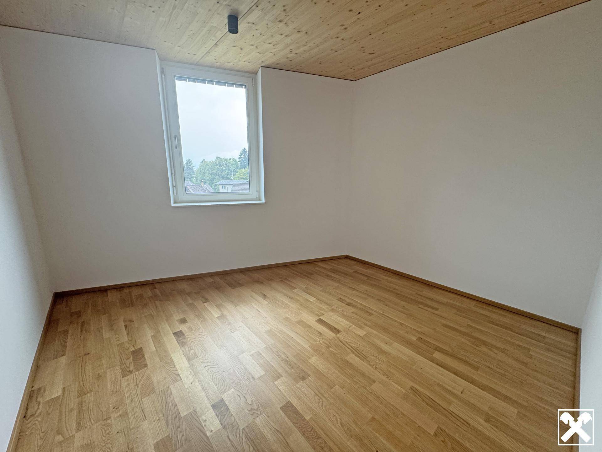 Gemütliches Zimmer mit Holzboden und einem Fenster, das viel Tageslicht hereinlässt.