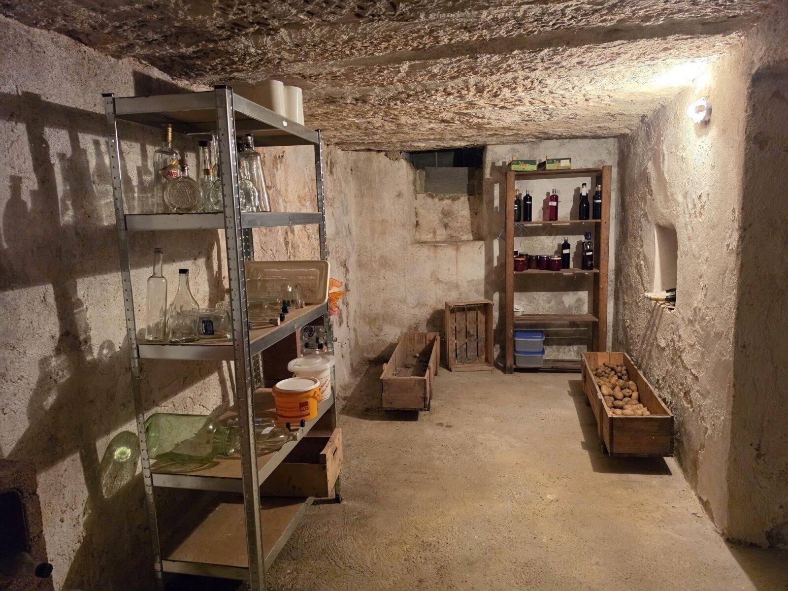 Rustikaler Kellerraum mit Regalen für Lagerung, ideal als Vorrats- oder Weinkeller.