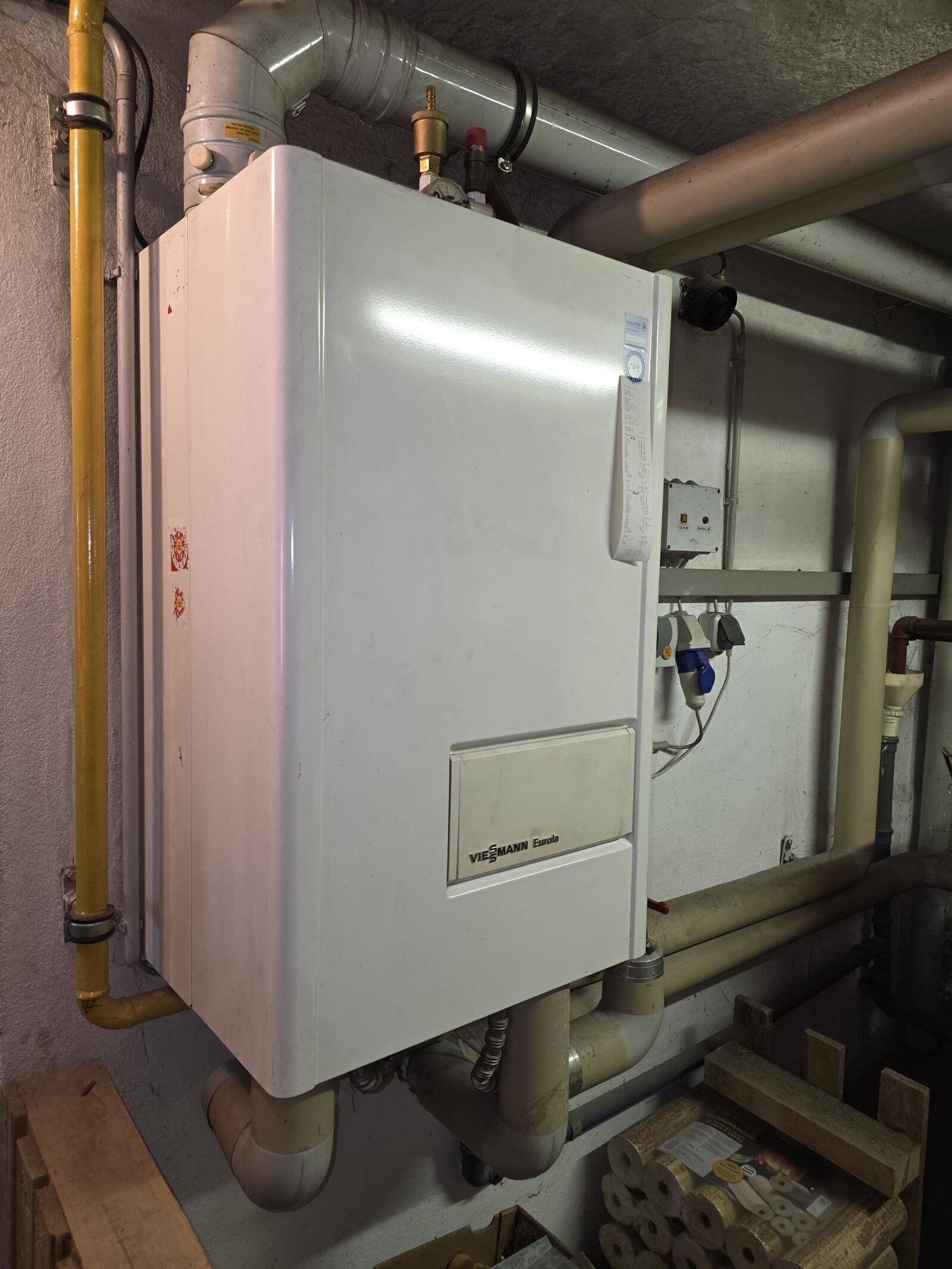 Weißer Viessmann Gaskessel in einem Technikraum, umgeben von Rohrleitungen.
