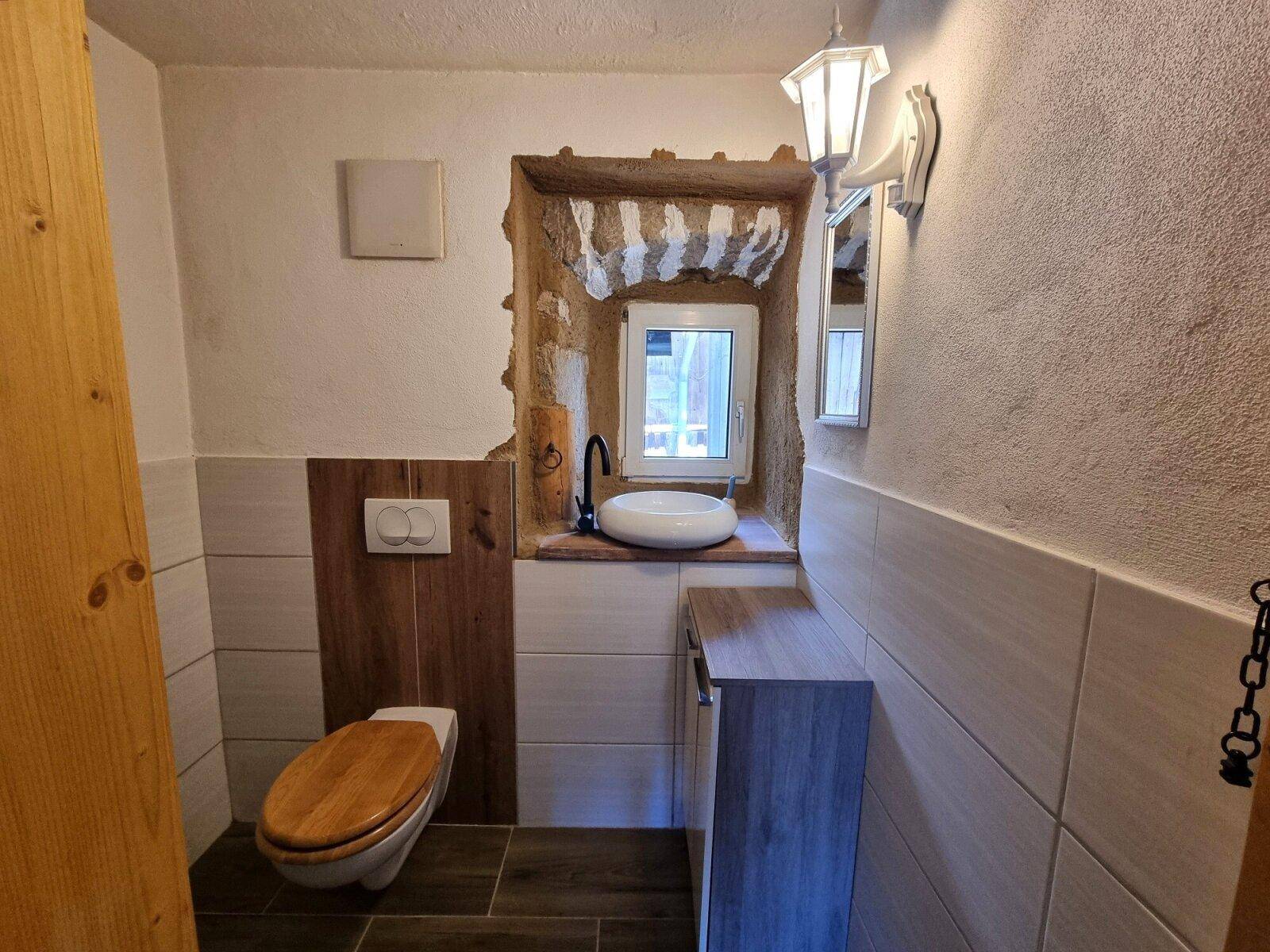 Kleines Gäste-WC mit Wand-WC, modernem Waschbecken und rustikalem Fensterrahmen.