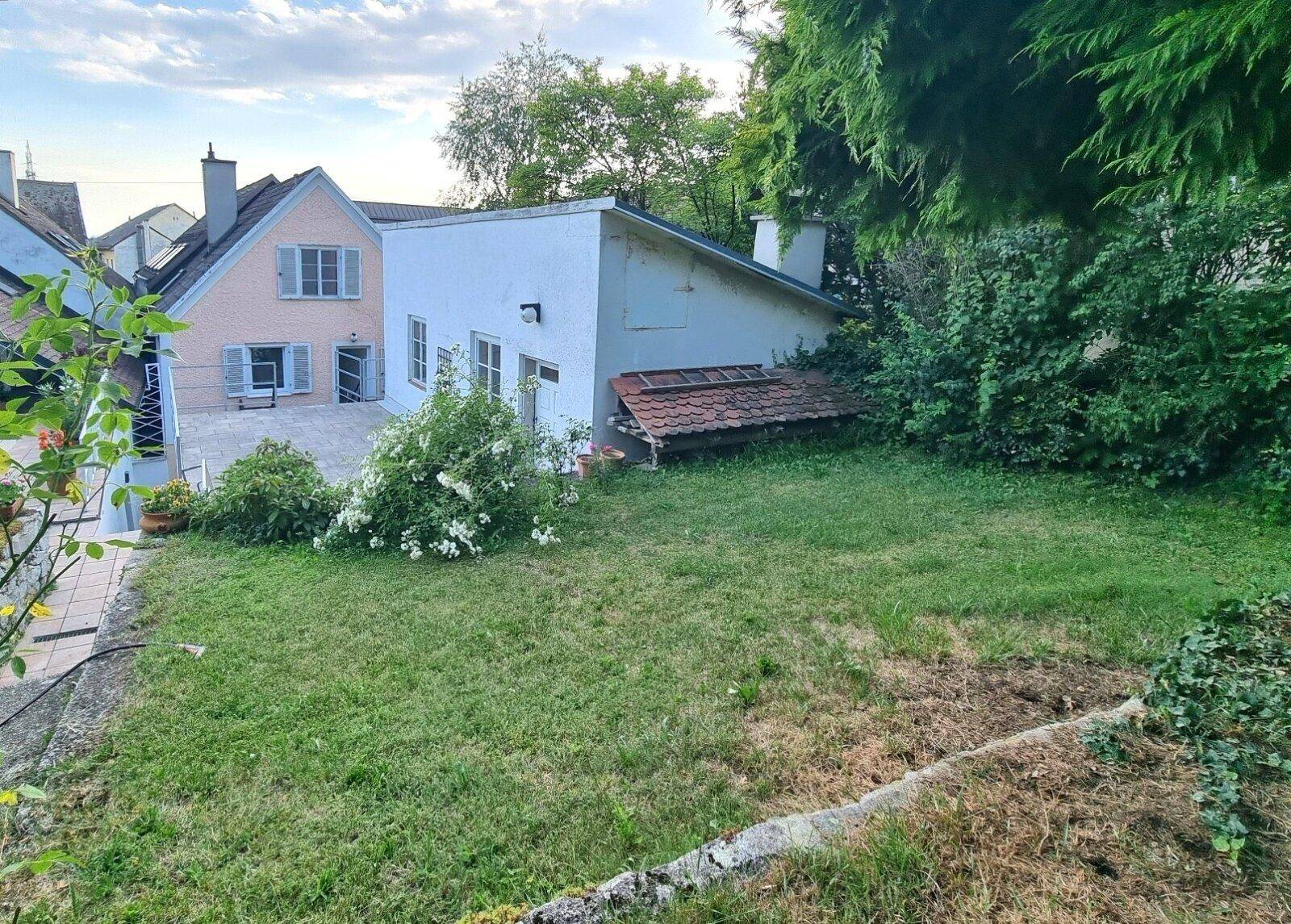 Gepflegter Garten mit Rasenfläche und Blick auf die Rückseite der Gebäude.