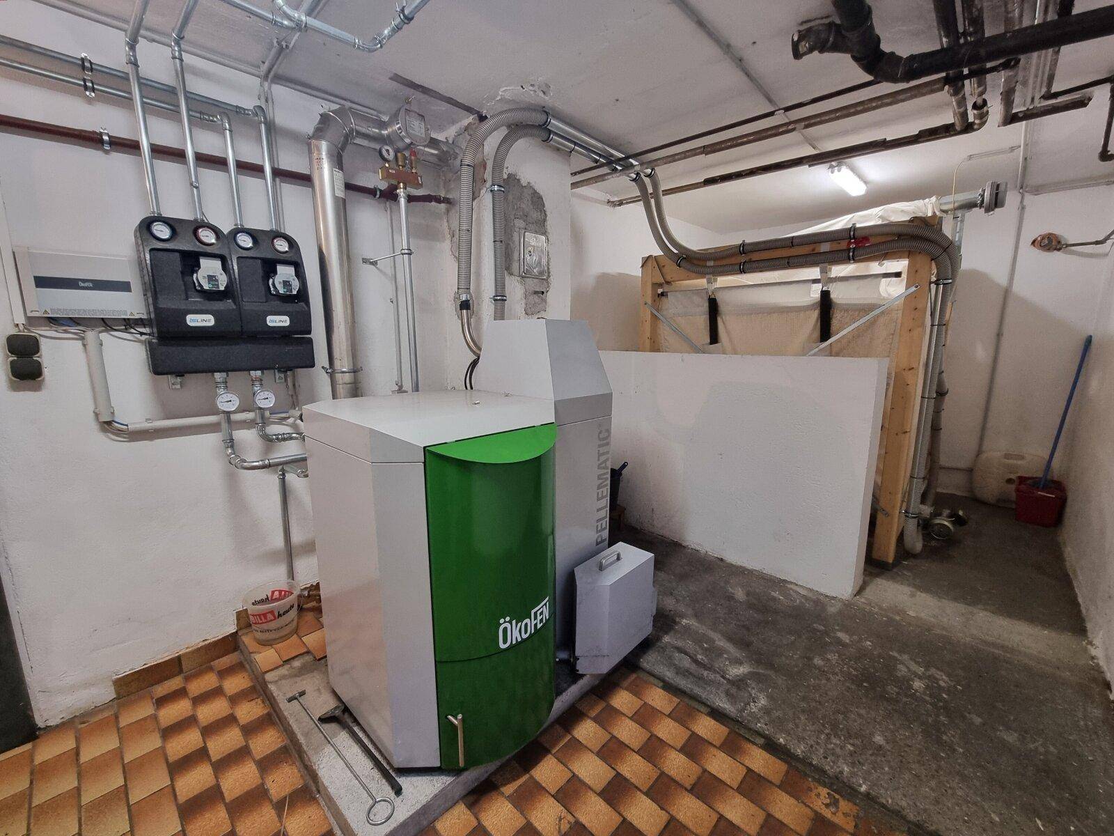 Heizungsraum im Keller mit moderner Pelletheizung und sichtbaren Rohrleitungen.