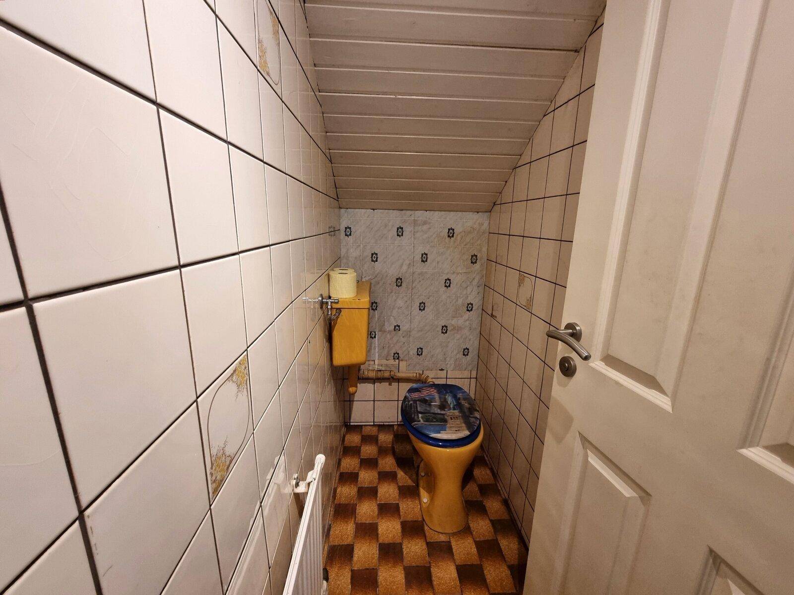 Kleines WC mit Fliesen, Dachschräge und farbiger Toilette.