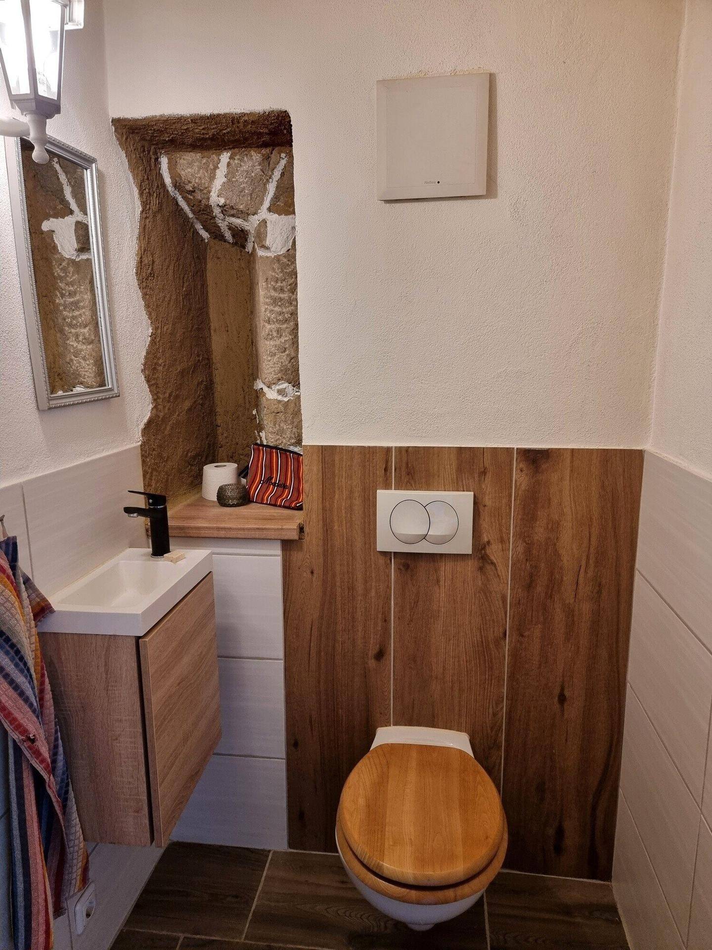 Detailansicht des Gäste-WCs mit modernem Waschbecken, Wand-WC und Holzdetails.