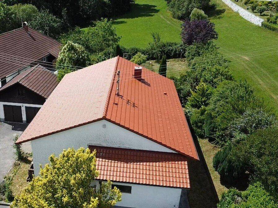 Dachansicht des Hauses mit roten Ziegeln und umgebender grüner Landschaft.