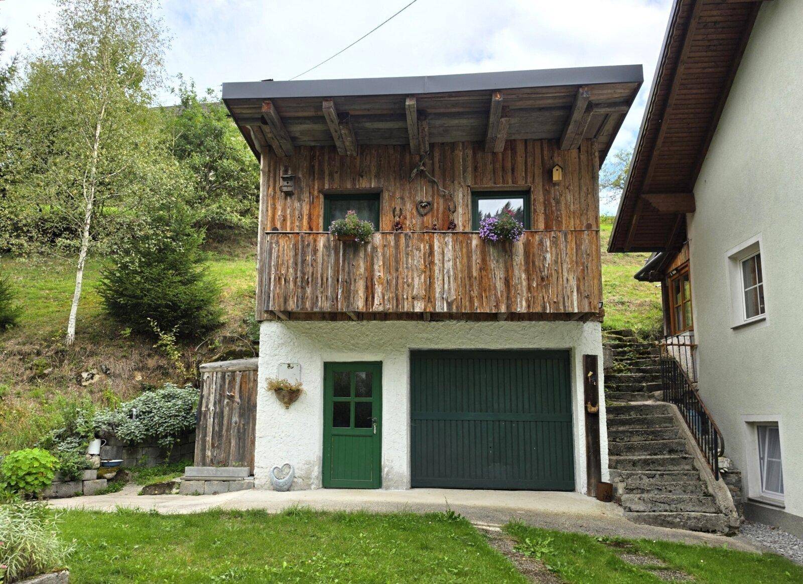 Separates Nebengebäude mit Garage und einem charmanten Holzbalkon im Obergeschoss.