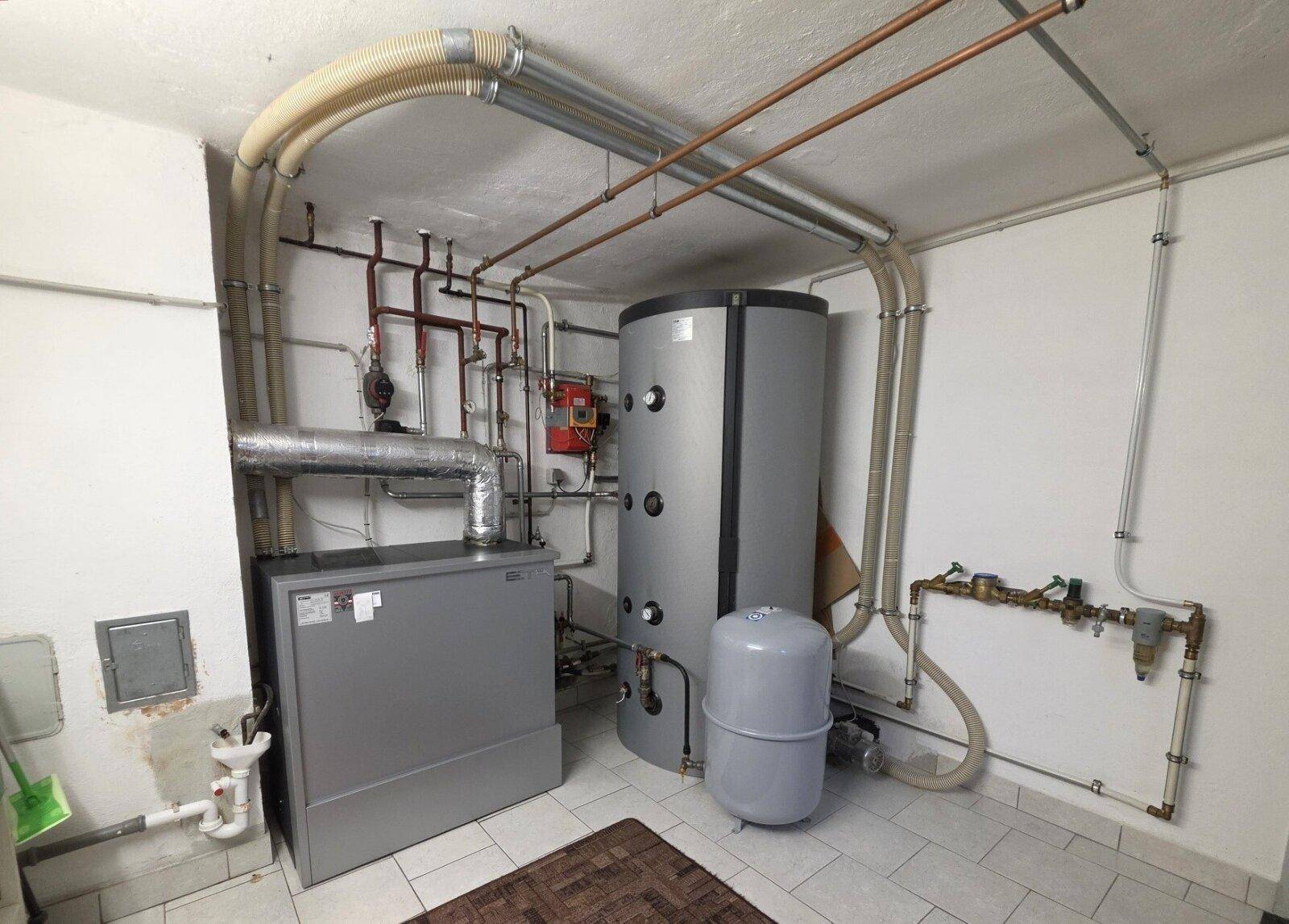 Heizungsraum mit moderner Heizungsanlage und Warmwasserspeicher.