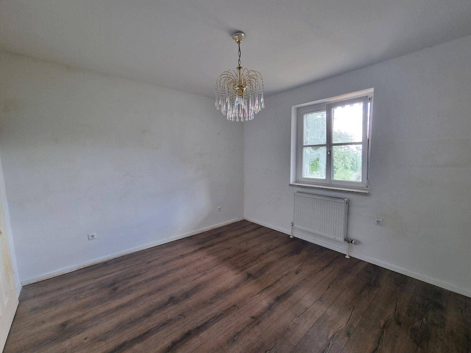 Helles Schlafzimmer mit Laminatboden, weißen Wänden und Kronleuchter.