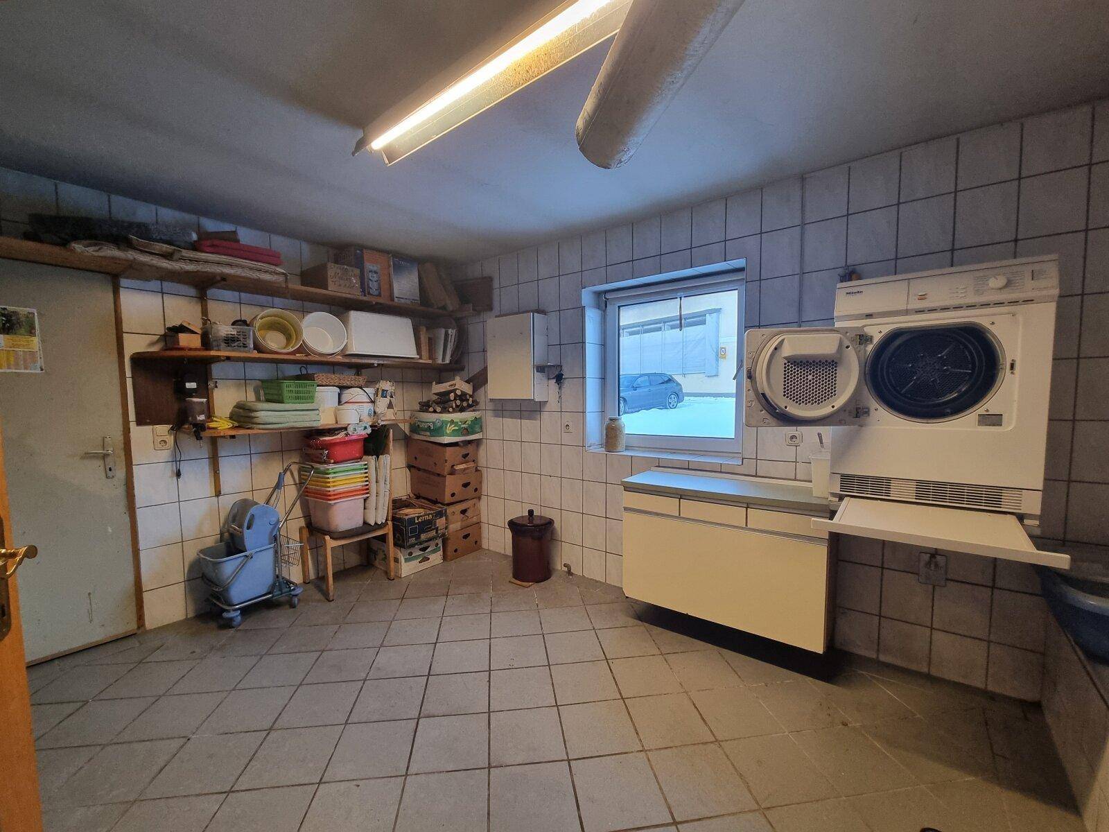 Hauswirtschaftsraum mit Waschmaschine, Trockner und gefliestem Boden.