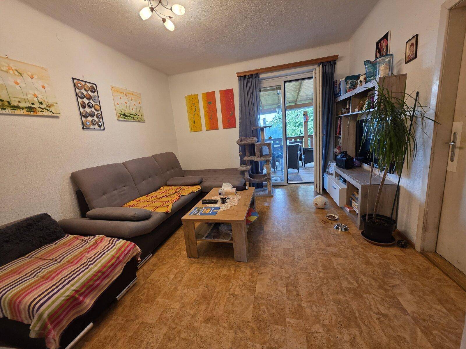 Gemütliches Wohnzimmer mit Sofa, Couchtisch und Zugang zu einem Außenbereich.