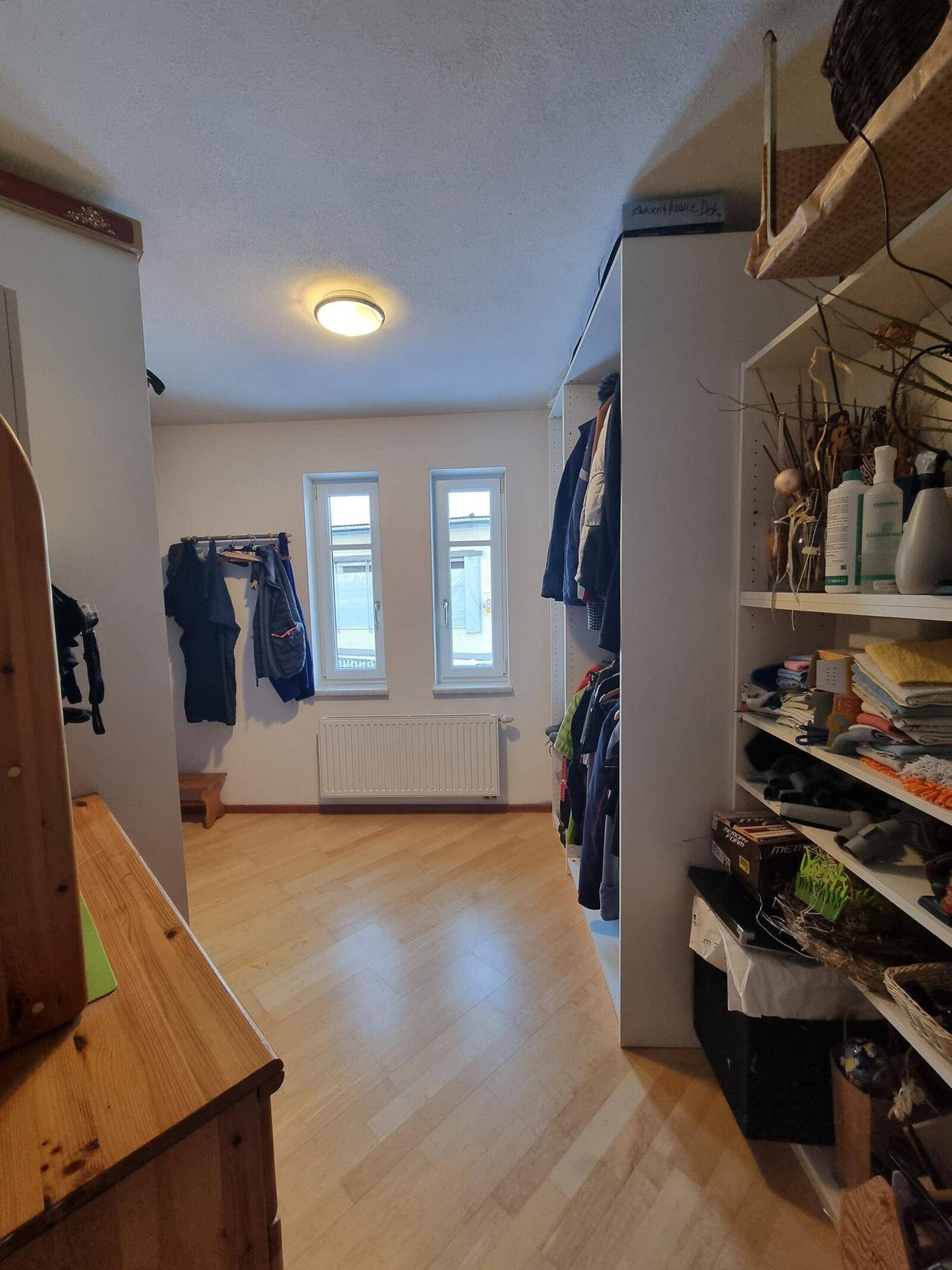 Ankleidebereich oder Schlafzimmer mit Regalen, Kleiderstangen und Holzparkett.